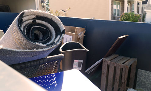 头顶的家庭垃圾在一个蓝色的40码垃圾箱