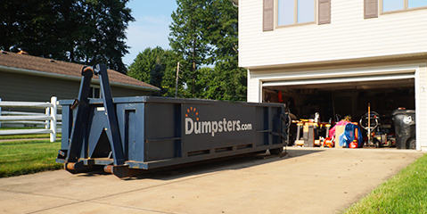 12 yard roll off dumpster sitting in driveway with open garage.