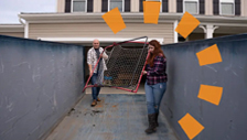 Two People Loading Debris in Dumpster