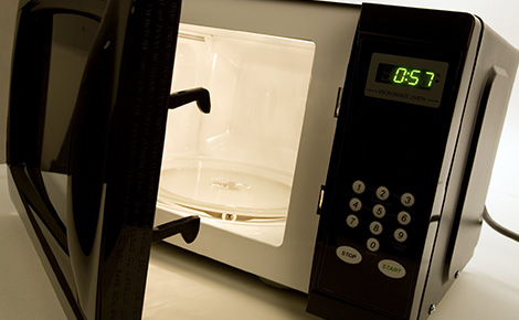 A black microwave on a counter with an open door.