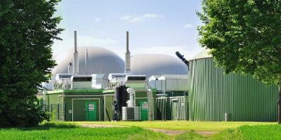 Anaerobic Digestion Plant With Two Trees and a Bright Green Field in the Foreground