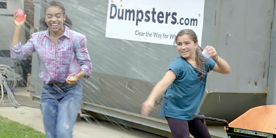 Kids throwing water balloons in front of Dumpsters.com dumpster.