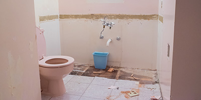 A bathroom stripped of a bathtub and sink.