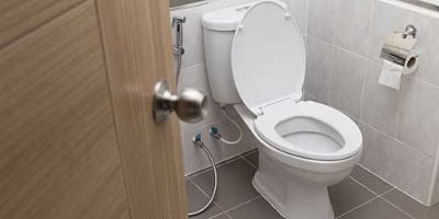 A White Toilet in a Tiled Bathroom.