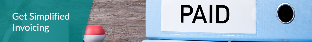 A light blue binder with “Unpaid” written on its side lying on a desk next to a coffee mug, a rubber stamp, a pen and a notebook.