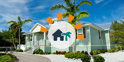 Blue Vacation Home with Palm Trees and Gravel Landscaping Underneath Clear Blue Sky.