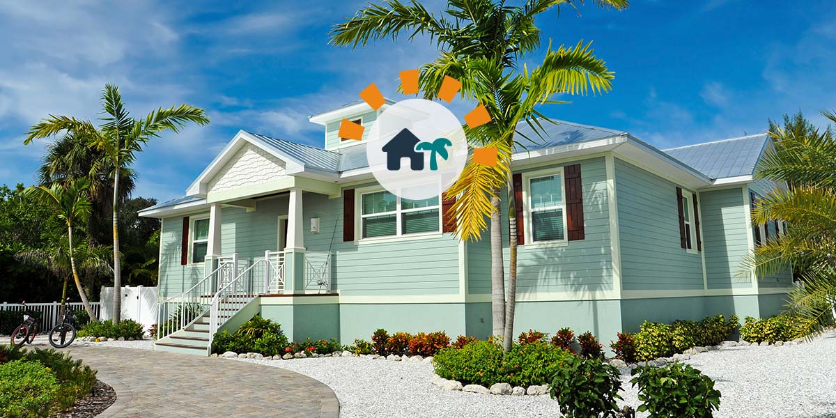 Blue vacation home with palm trees and gravel landscaping underneath clear blue sky.