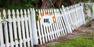 Old broken white fence leaning over needing removal.