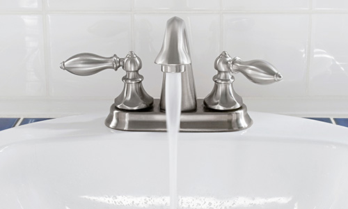 A brushed nickel bathroom sink faucet and handles.