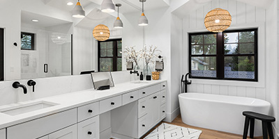 Beautifully remodeled bathroom with newly installed wood flooring, white cabinetry and modern black hardware.