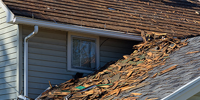 A two-story home with the upper story's roof shingles removed.