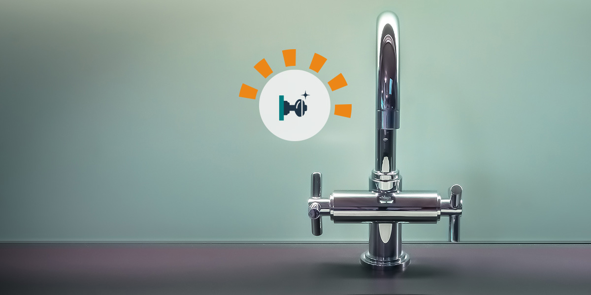 A chrome faucet on a black counter with green walls.