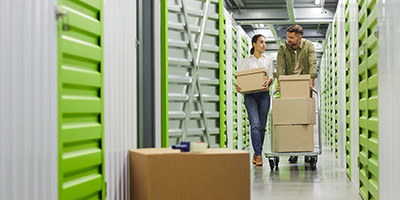 A couple holding boxes cleaning out a storage unit. 