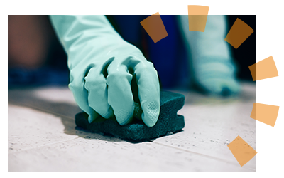 A hand cleaning a bathroom floor that is ready for new tile installation. 