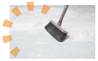 A black broom sweeping the concrete flooring of a storage unit