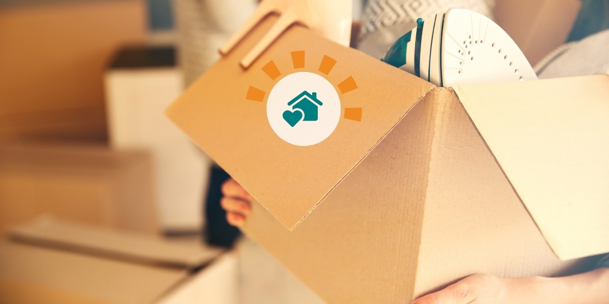 A person carrying a cardboard box full of items out of their home.