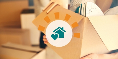 A person carrying a cardboard box full of items out of their home. 