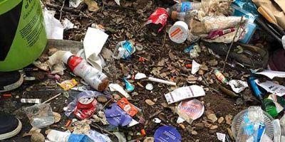 Ground heavily littered with food wrappers, plastic bottles and other trash.