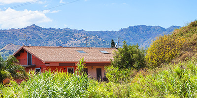 House with an Overgrown Yard With a Scenic Mountain Backdrop.