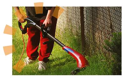 A red weed whacker being used by a chain-link fence.