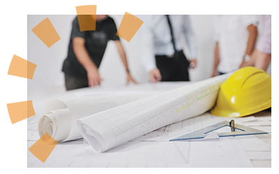 Four employees standing around a table that has a yellow hard hat on it and construction plans.