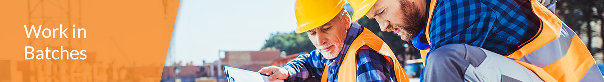 Three construction workers studying blueprints at a work site.