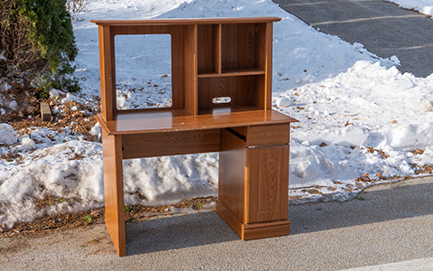 Desk sitting on a sidewalk on a snowy day.