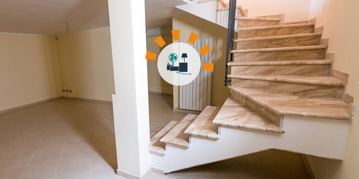 A wood staircase leading to a clean and decluttered basement. 