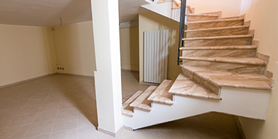 A wood staircase leading to a clean and decluttered basement. 