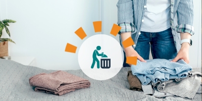 A woman clearing out her closet with jeans and sweaters laying on the bed. 