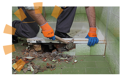 Closeup view of worker demolishing surrounding tile to pry up the shower floor pan.