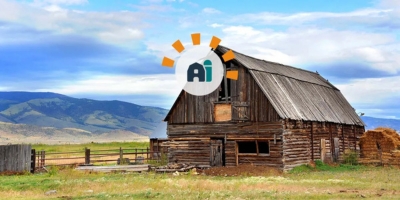 A decaying barn in a grassy field with blue skies.