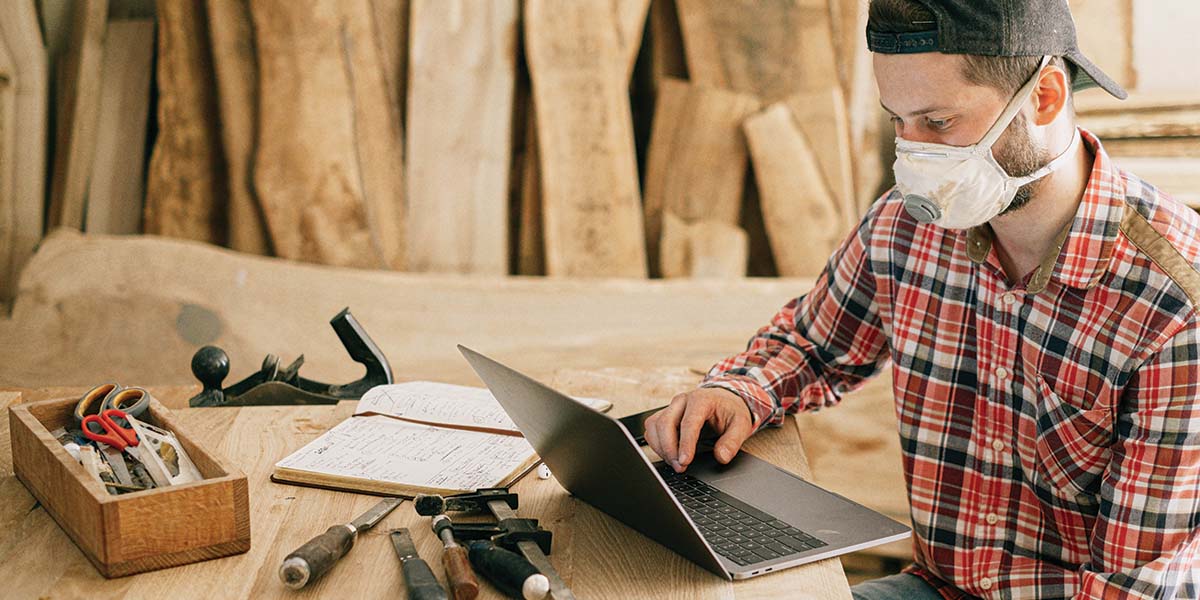 Homeowner researching DIY project on computer surrounded by tools.