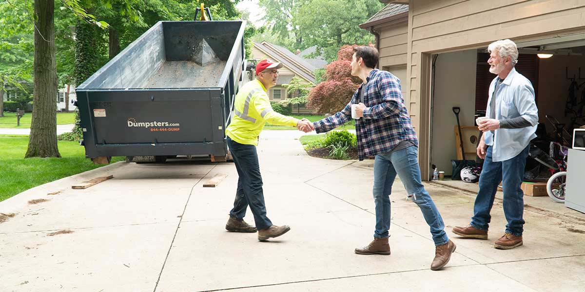 Dumpster.com Roll Off Truck Driver Matt Snyder Shakes Hands With a Customer During a Roll Off Dumpster Delivery.