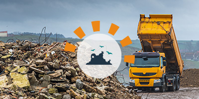 Orange dump truck tipping load into a landfill with debris in the foreground.