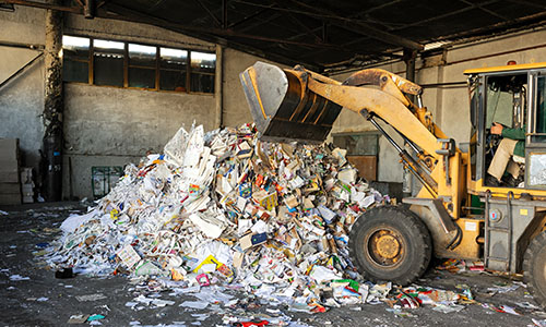 An excavator dumping trash at a transfer station. 