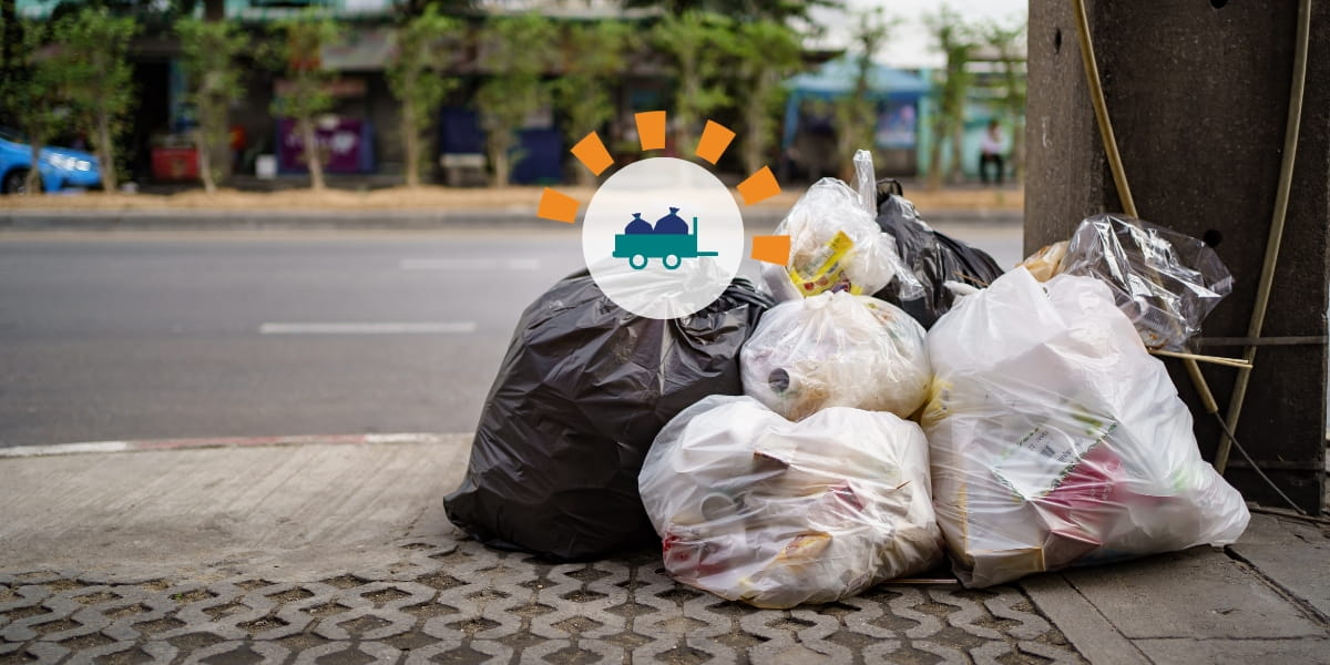 A pile of filled trash bags sitting on the side of the street.
