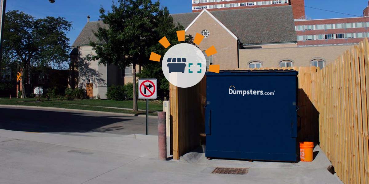 Dumpsters.com blue commercial dumpster in a wooden corral.