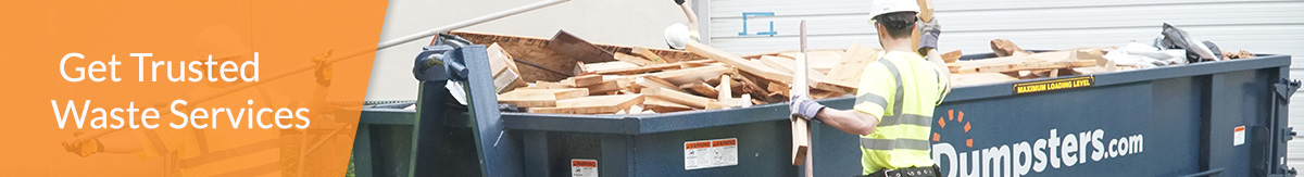 Worker next to a Dumpsters.com roll off dumpster sitting on a construction site.