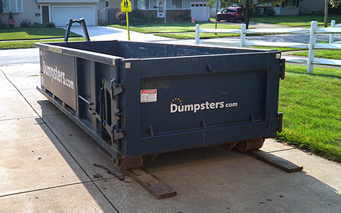 Empty Dumpsters.com dumpster sitting in a driveway.