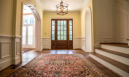 An updated vintage foyer in a home with a ornamental rug and wood accents. 