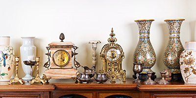 Estate sale with valuable, antique clocks, vases, candlesticks, cups and wooden dresser.