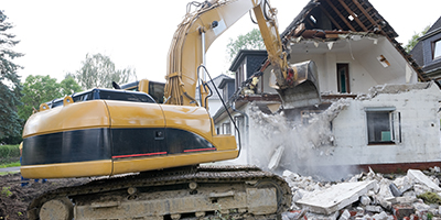 Hydraulic excavator destroys upper floor of a house.