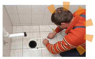 A plumber removing leftover caulk after removing a toilet bowl.