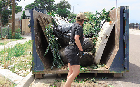 Extreme Community Makeover volunteer loading debris into a Dumpsters.com dumpster.