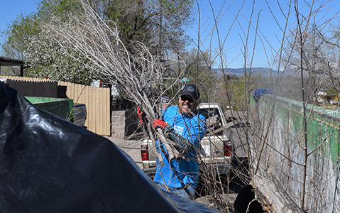 Extreme Community Makeover volunteer loading debris into a Dumpsters.com dumpster.