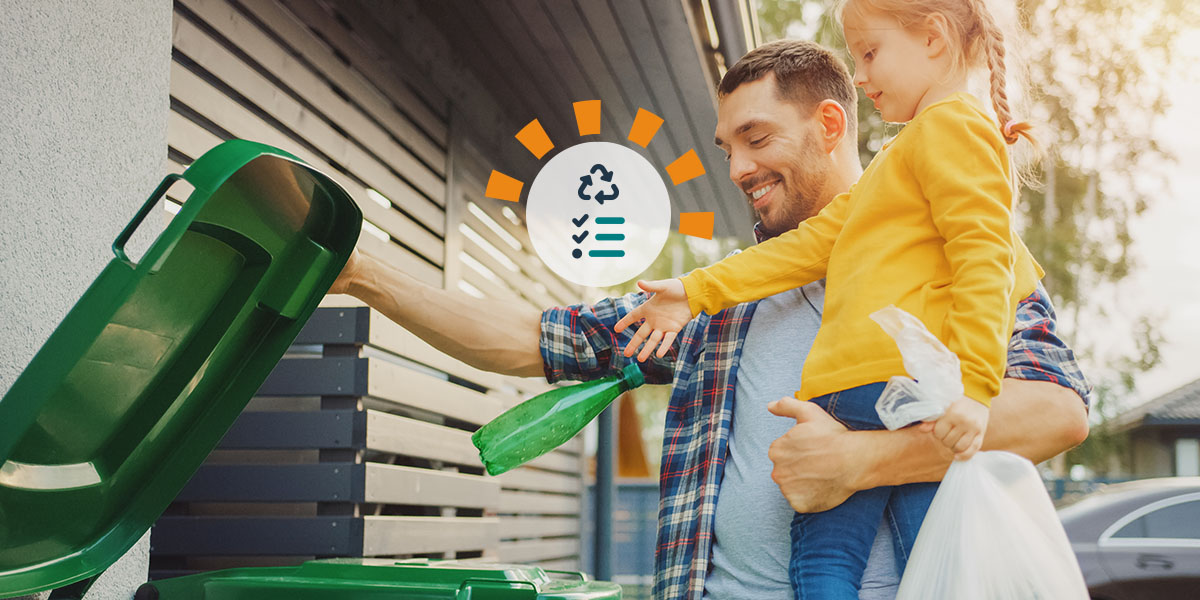 A father and daughter properly recycling materials outside. 