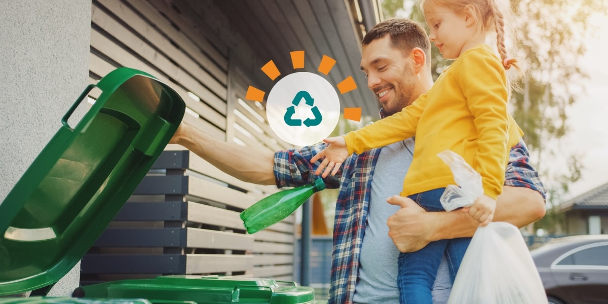 A father and daughter properly recycling materials outside. 