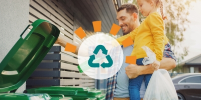 A father and daughter properly recycling materials outside. 