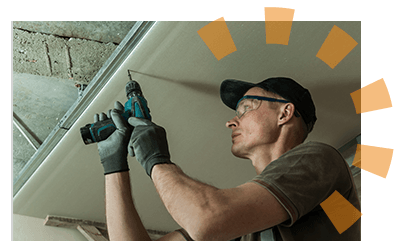 Man with an electric drill installing basement ceiling.